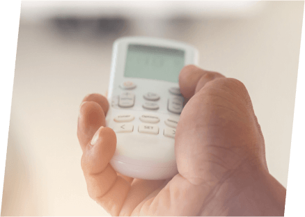 A hand holding a remote control, potentially used for monitoring refrigerant levels in an HVAC unit.